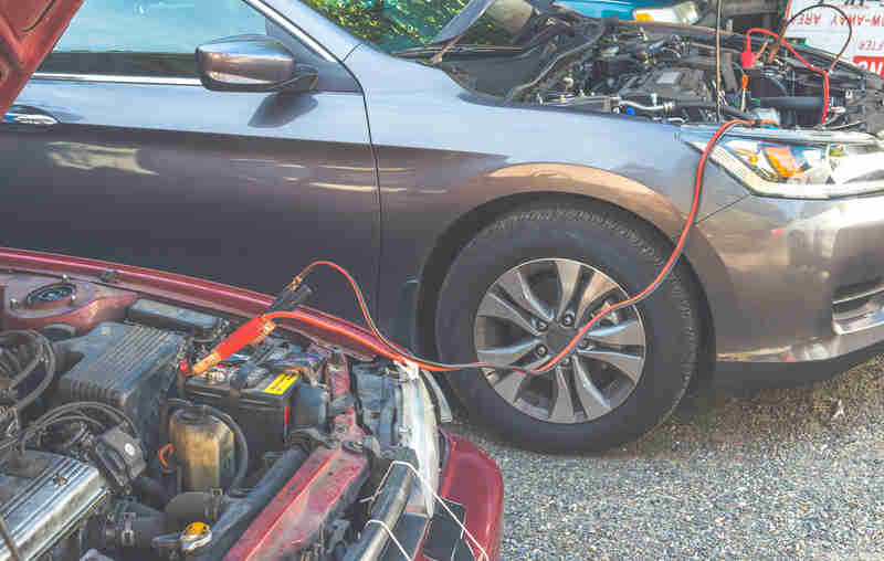Two jumper cables attached between old car and new car